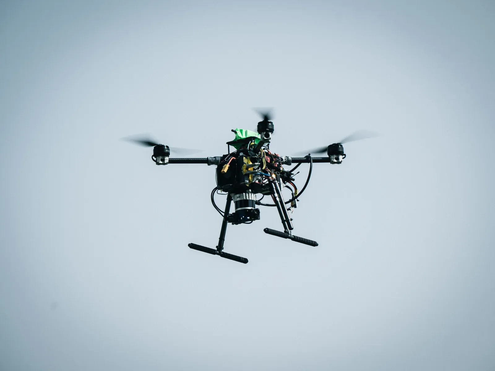 Close-up of the research quadcopter in flight, showing its exposed electronics, sensors and landing skids.